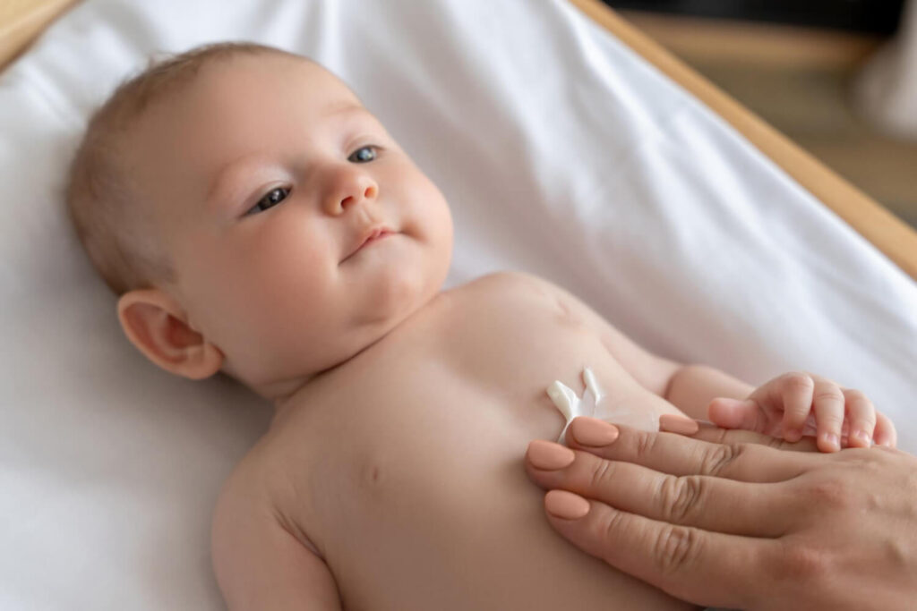 maman applique le liniment sur le ventre de bébé