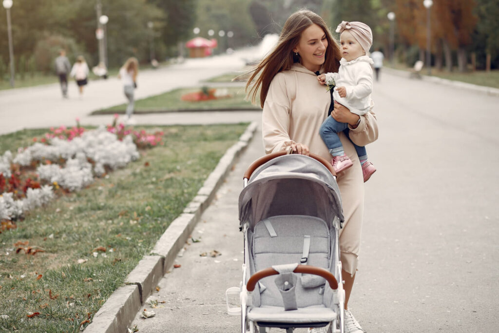 maman porte son bébé et tire la poussette